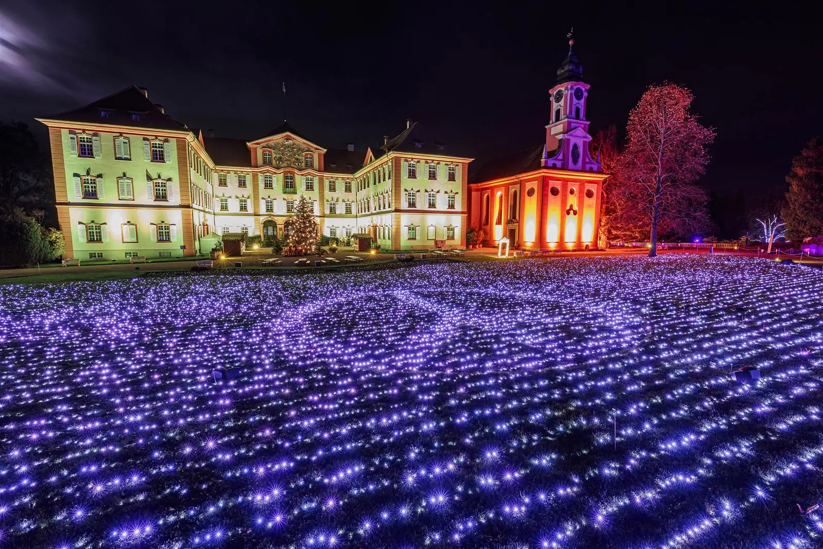 Christmas Garden auf der Insel Mainau: Schloss und Kirche über einem Meer aus Lichtpunkten