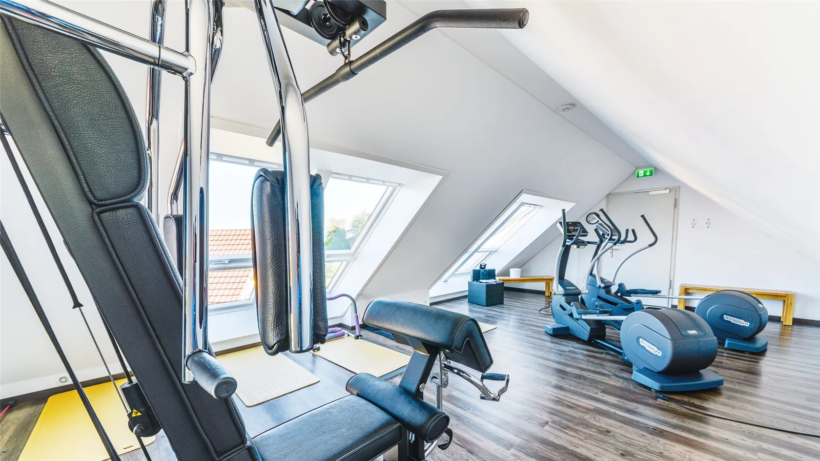 Fitnessraum mit Kraftgerät und Crosstrainern unter der Dachschräge