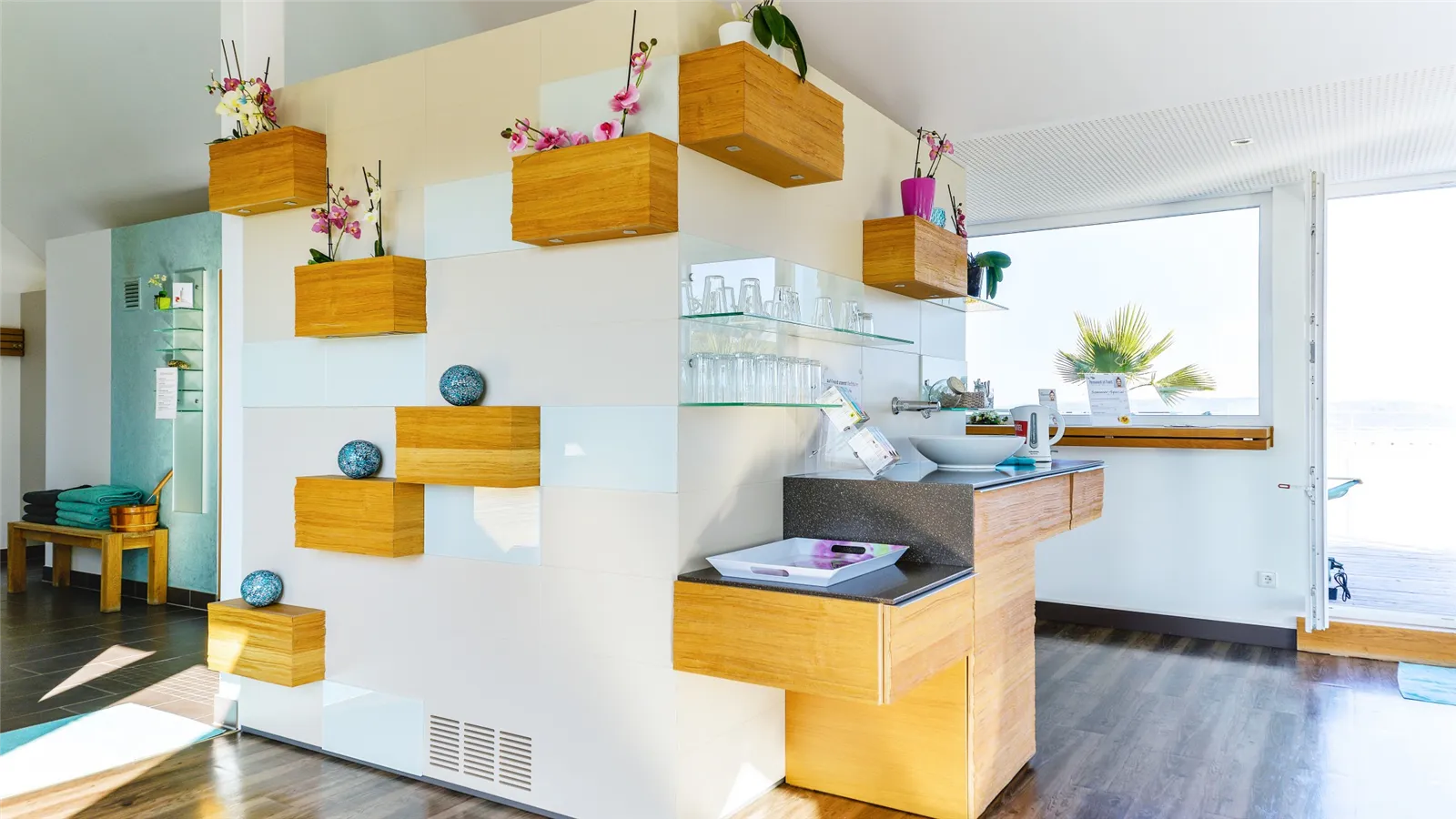 Holzfächer mit Orchideen und Ablage mit Gläsern im Ruhebereich